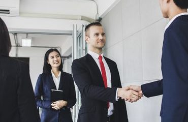 Manager, businessman, Europe investor or boss shake hand  with Asian Entrepreneur and  successful  big project deal in meeting  by interpreter standing near to translate.